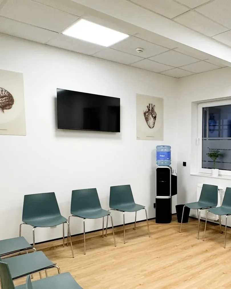 Wartezimmer der Hausarztpraxis Tzanis mit Bildschirm für Gesundheitsinformationen